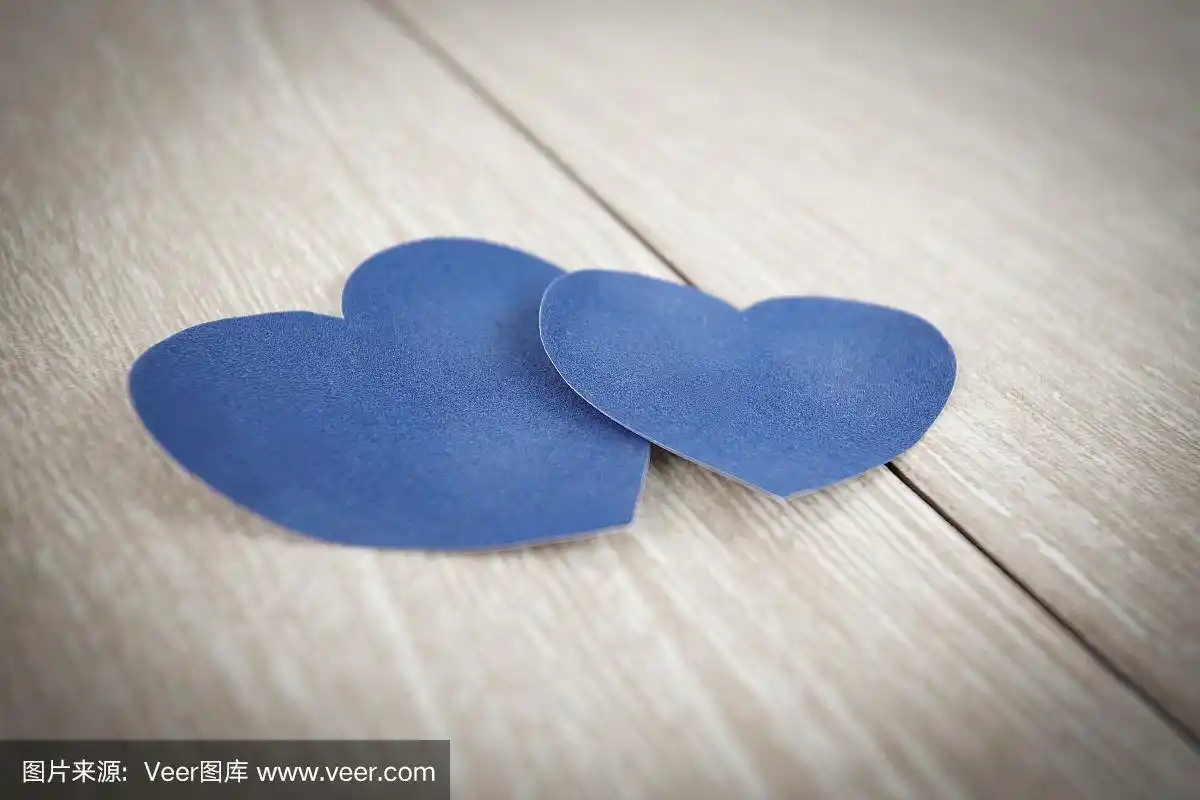 蓝色的心形纸在浅色的木制背景上