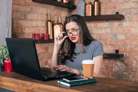 阁楼内部的笔记本电脑上努力工作年轻漂亮的女人在健身房用哑铃做运动