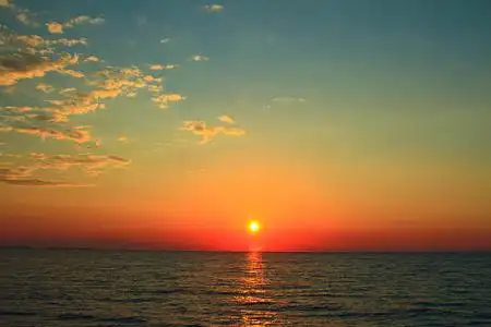 明亮的日落与黄色的太阳在海面之下在海面冉冉升起的太阳的光线非常