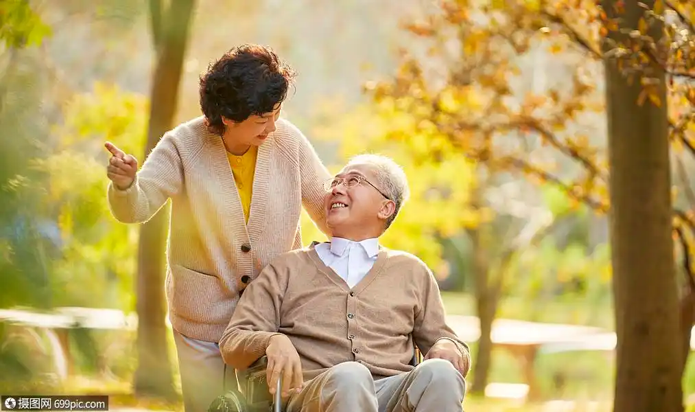 老年夫妇相伴逛公园对视陪伴轮椅