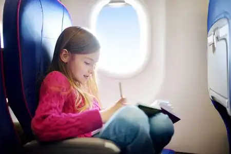 孩子坐飞机的窗户和用彩色铅笔画一幅画.出国游玩的孩子们照片