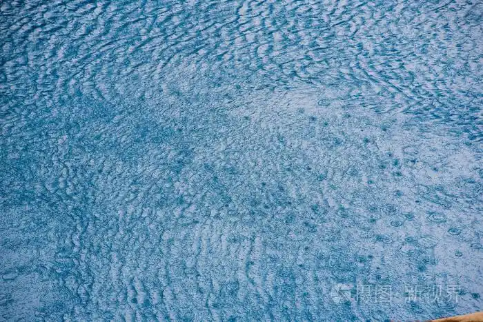 带有蓝色纹理背景的池中的小波浪和雨滴的水