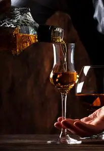 酒保在旧酒吧柜台上用小玻璃杯倒酒.