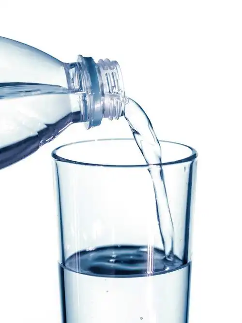 水倒进一个绿色软焦点背景上的玻璃杯