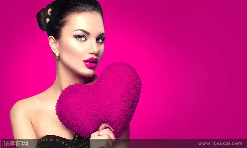 玫红色背景上拿着玫红色爱心的美女高清图片