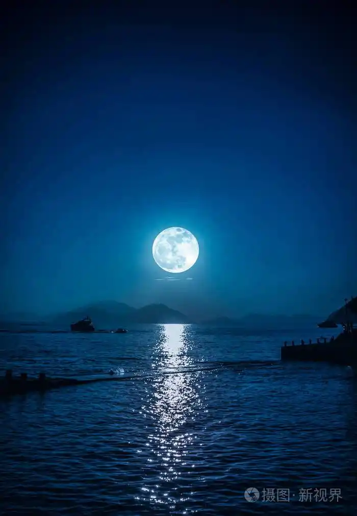 夜晚宁静海水中的小船和月亮的风景