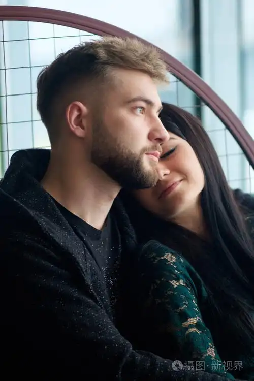 年轻漂亮的青少年白种夫妇坐在靠近窗口和拥抱 e