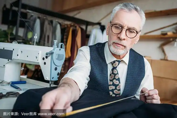 英俊的裁缝在缝纫车间测量布料