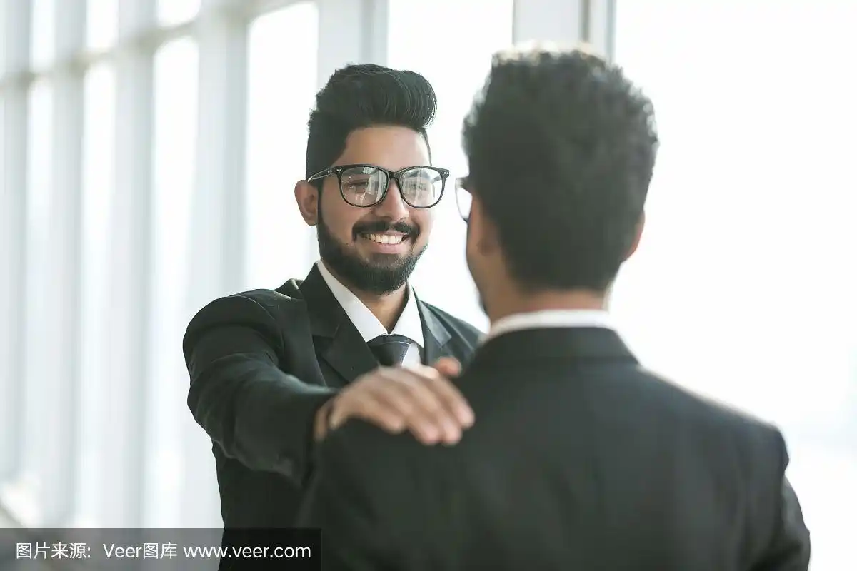 印度商人在办公室里拍拍同事的肩膀微笑