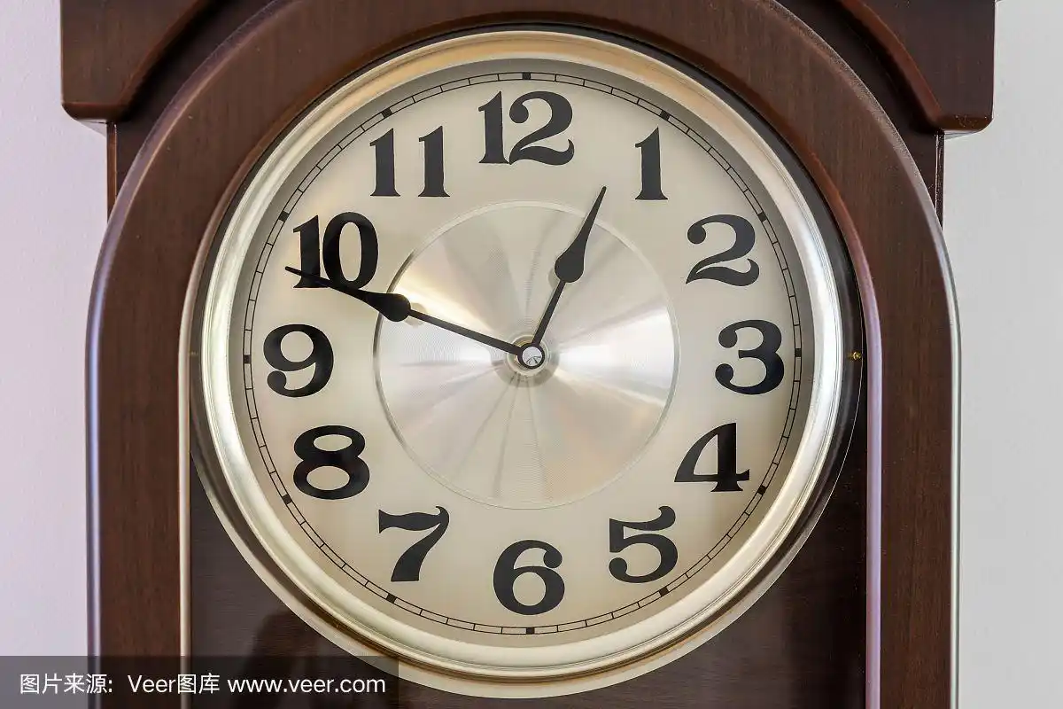 近距离微距观察的棕色时钟与光时钟面显示几乎12点50分.时间的概念.