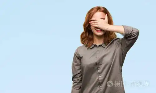 年轻美丽的女人在孤独的背景下微笑着, 笑着用手捂着眼睛惊讶.