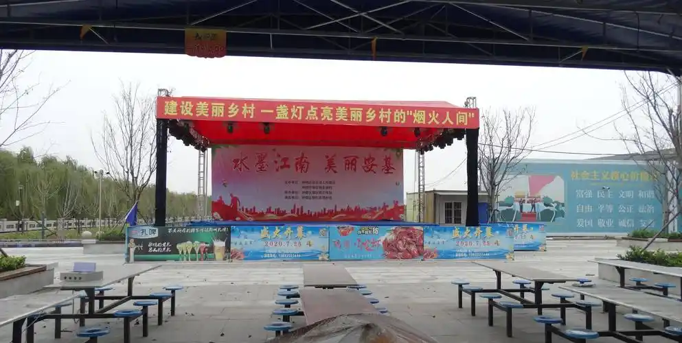安基村最北边的空地上还有个临时搭建的大舞台,舞台下几十张餐桌整齐