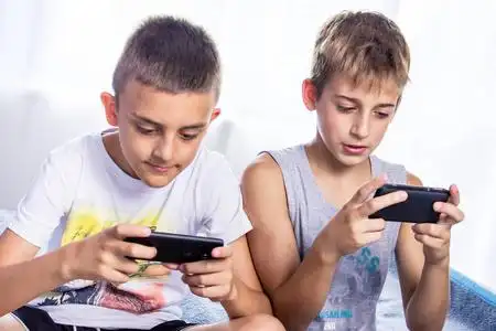 孩子们,兄弟们在智能手机上玩游戏.网络成瘾照片