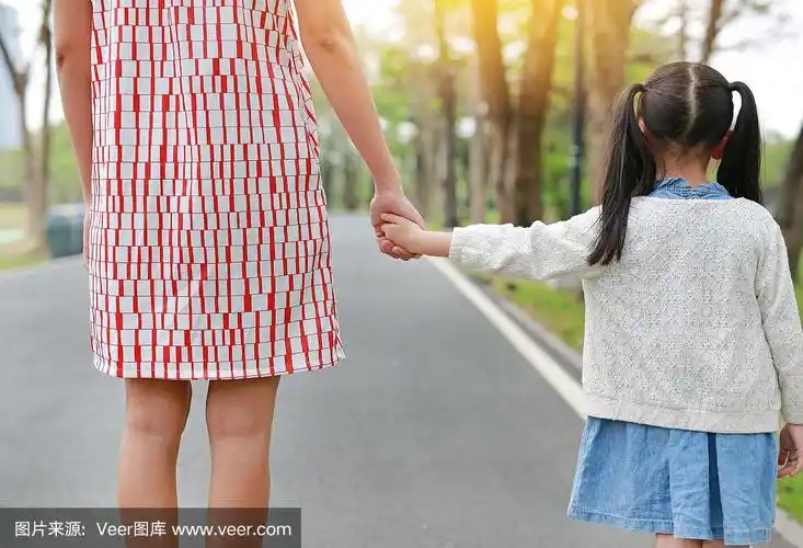 特写妈妈和女儿手牵手在户外自然花园.后视图.