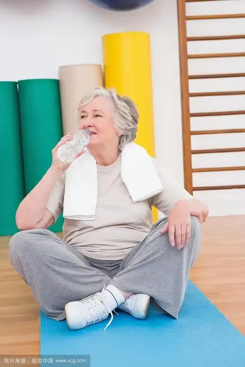 老年妇女在运动垫上喝水