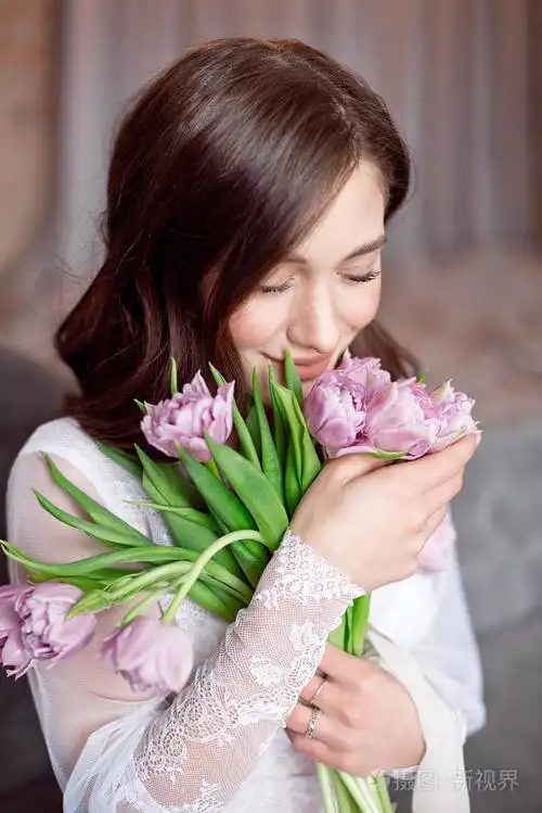 年轻美丽的黑发女孩手里捧着春天的郁金香花束