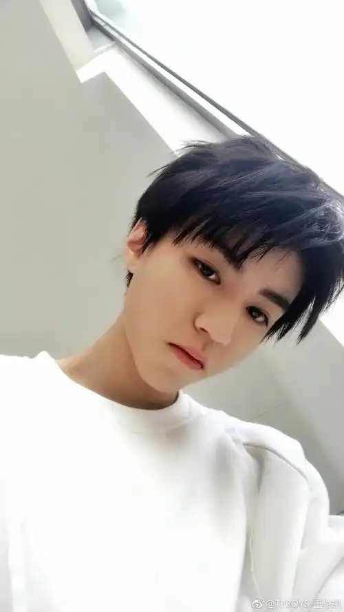 照片中王俊凯在卧室幽暗的灯光下自拍,眼神温柔,十分帅气.