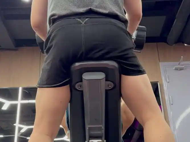 健身房里的力量训练 | 穿着背心短裤的男人在举重器械上锻炼身体