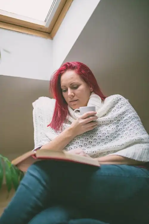 红头发的女人坐在椅子上喝着咖啡.图片下载