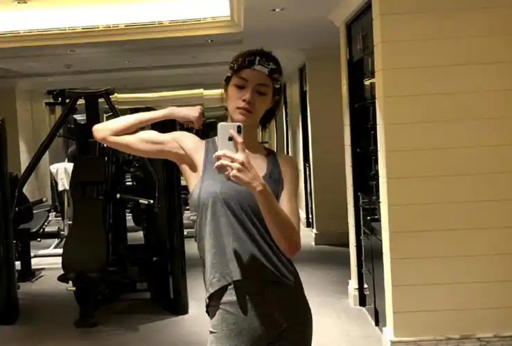 照片中,钟楚曦身穿黑色运动背心和短裤,边做瑜伽动作边自拍,马甲线