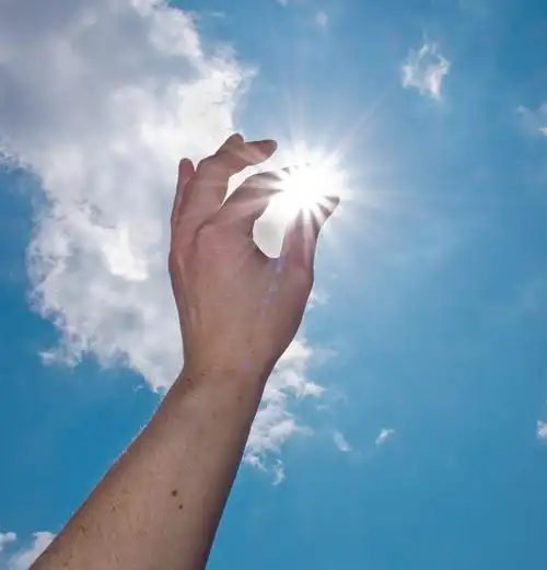 一只手在蓝色的天空中捕捉星期二的太阳图片下载