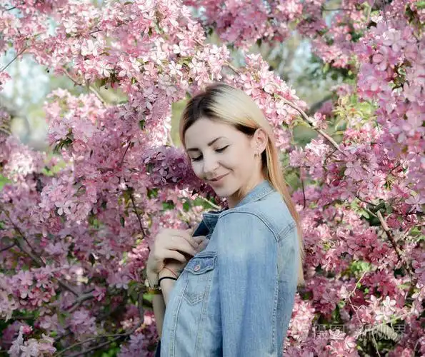 美丽微笑的年轻女子开花的春天树附近.