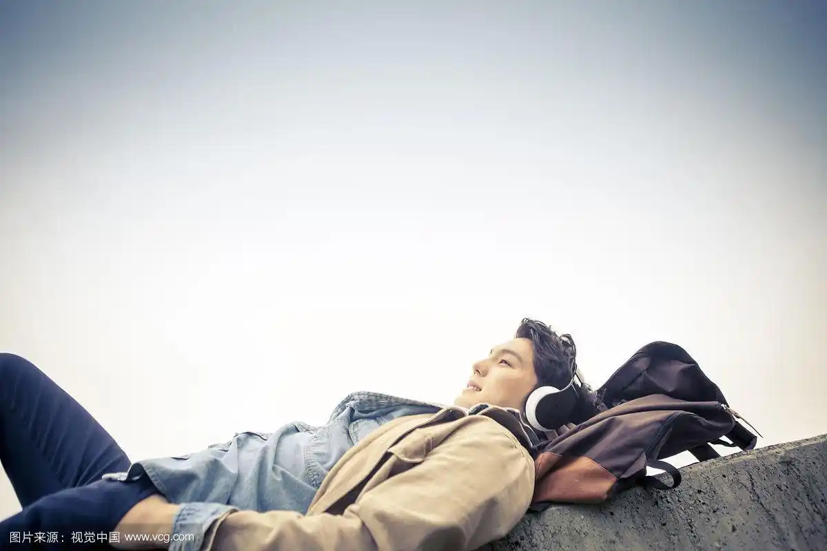 一个人躺在海边用耳机听音乐的照片