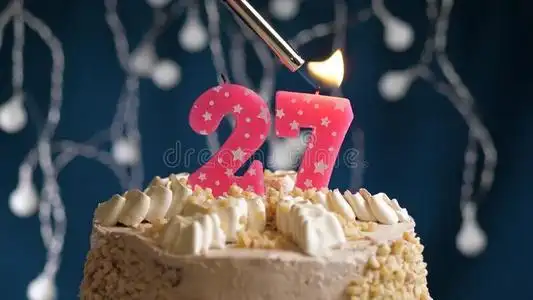 生日蛋糕和27数字粉红色的蜡烛向蓝色巴克格雷德.aux.能够照片