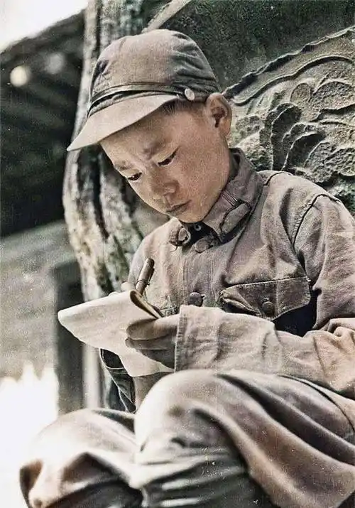 图为一名红军的少年兵在写东西的珍贵照片,从照片中可以看出这位战士