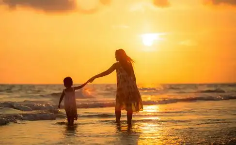 母亲带着女儿在海滩上照片