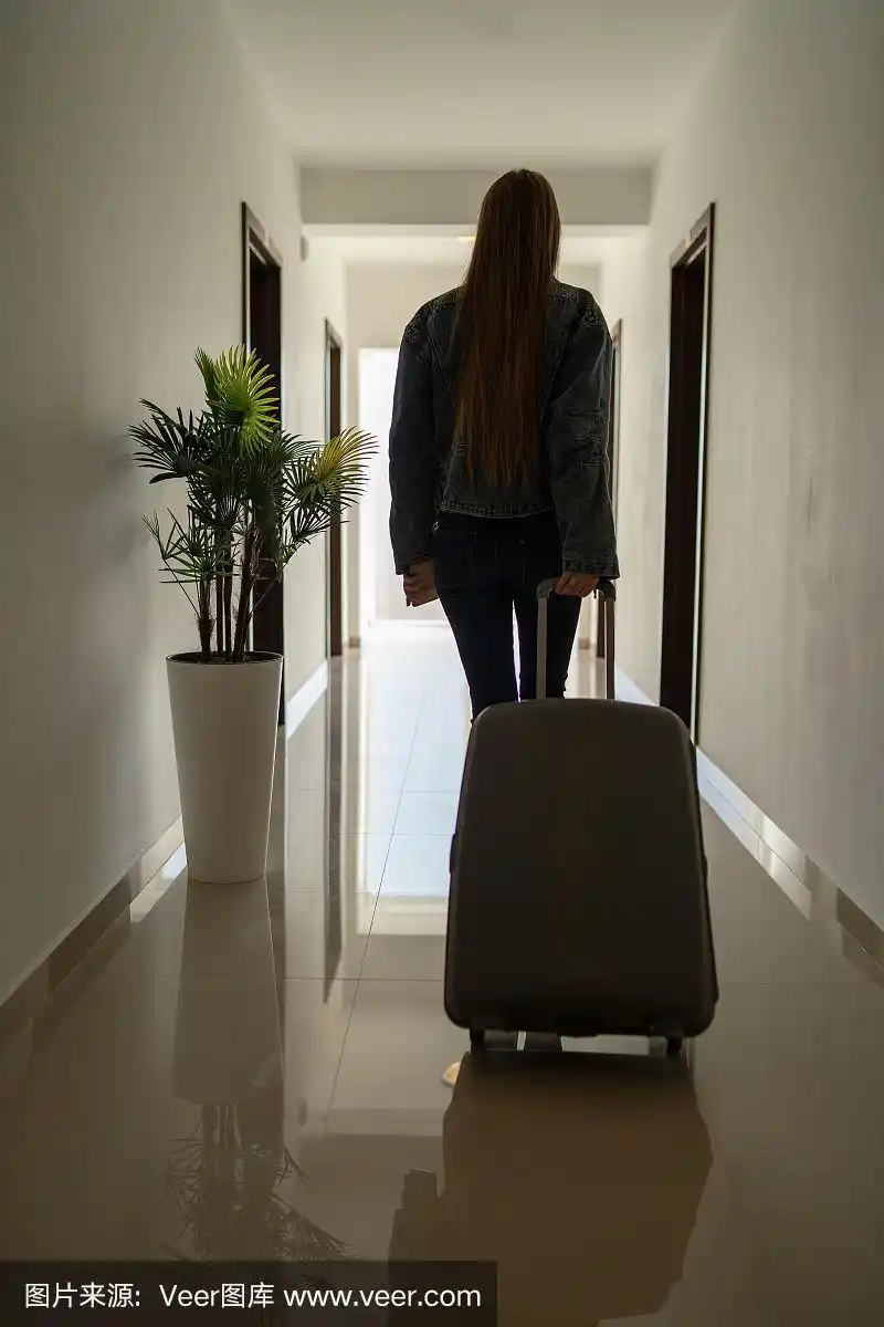 年轻漂亮的女孩的剪影背影女女人走在明亮的大厅大厅对着窗户在酒店或