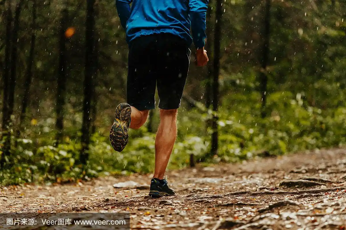 男跑步运动员在雨中奔跑森林小径