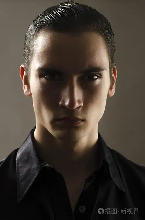 一个美丽的年轻男子肖像穿着一件黑色衬衫.在阴影中的人脸