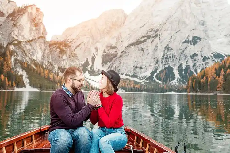 三个快乐的旅行者在一个湖上的木船在山上度假和旅游在意大利白云石的