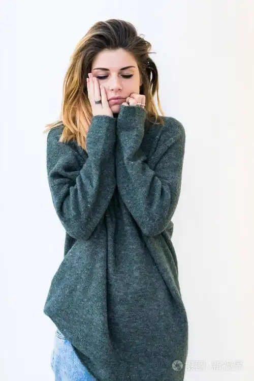 在大的灰色毛衣和茂密的头发,捂着脸用她的双手,降低她的眼睛向下