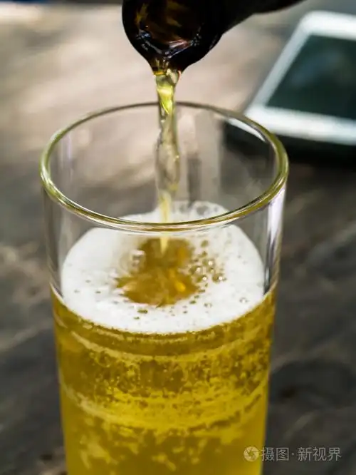 啤酒涌入木制的桌子上的玻璃