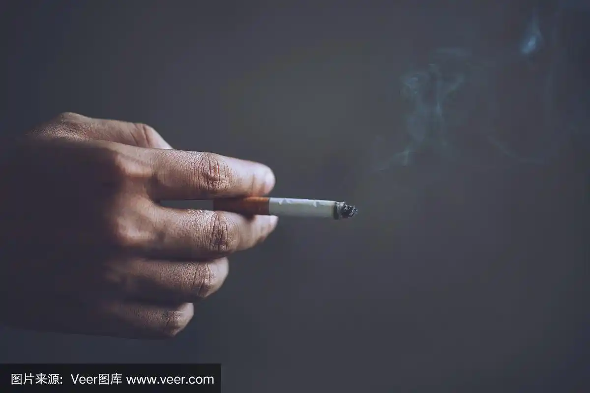 手里拿着烟的男人.香烟烟雾扩散.暗的背景