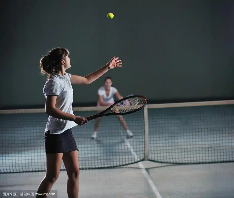 年轻的女孩在室内网球场打网球