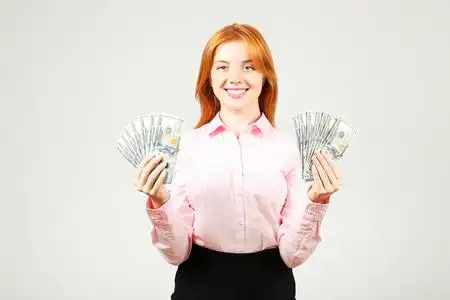 年轻漂亮的红发女人的肖像, 拿着一大把的钱持有100美元的钞票栈像