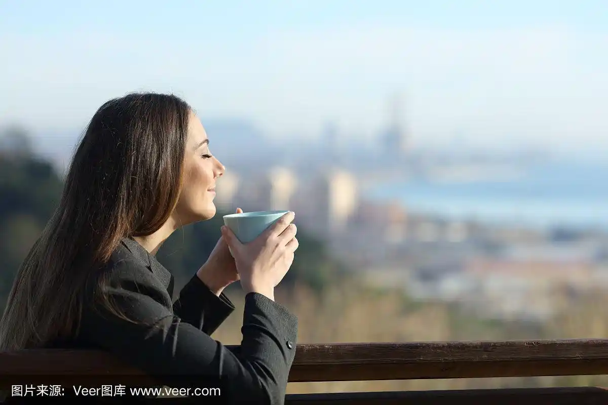 悠闲的女商人坐在长凳上喝咖啡