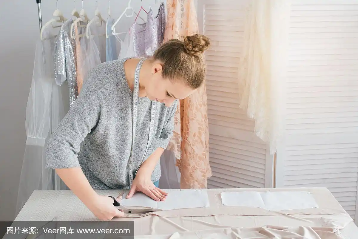 年轻的女裁缝裁剪布料做衣服