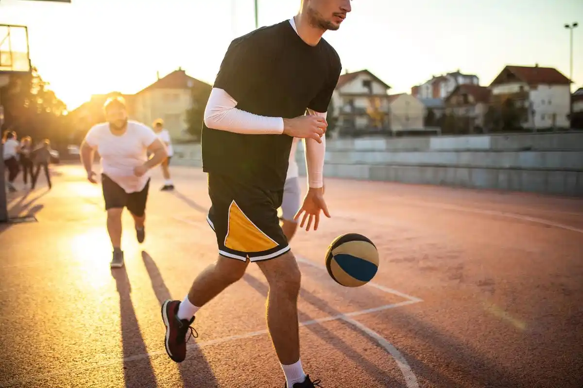 夏天的午后,阳光灿烂,翠绿的草地上,一群年轻人在打篮球.