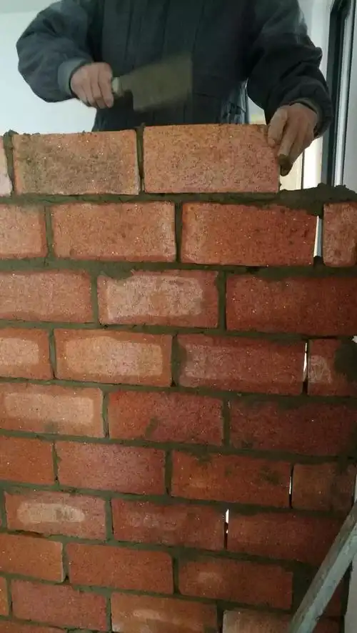 图中泥工师傅在立砖砌墙,这个墙比较薄,需要砌一半等干透后再往上砌