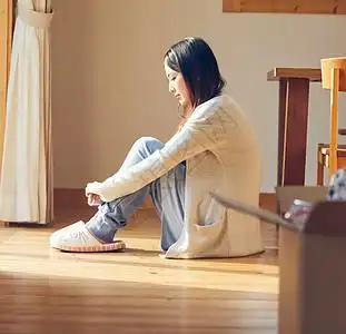 抱膝坐在地板上发呆的年轻女性图片素材