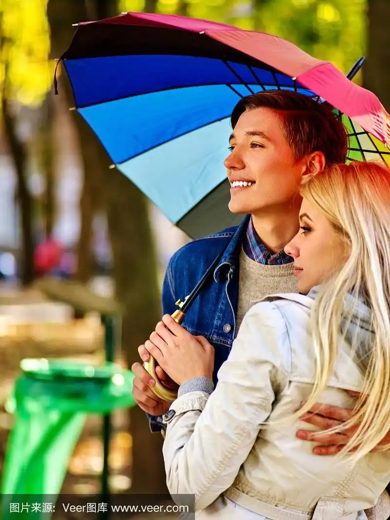 情侣在秋天公园的伞下约会.