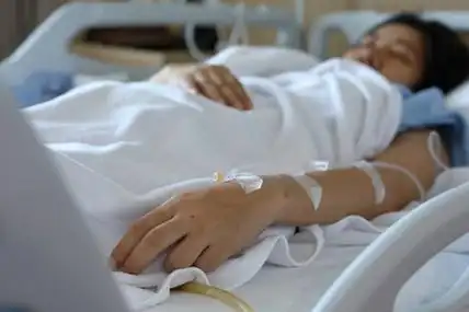 床治疗女患者卧床休息,手用静脉滴注生理盐水静脉注射治疗疾病照片