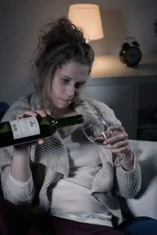 在室内喝酒的悲伤的女人