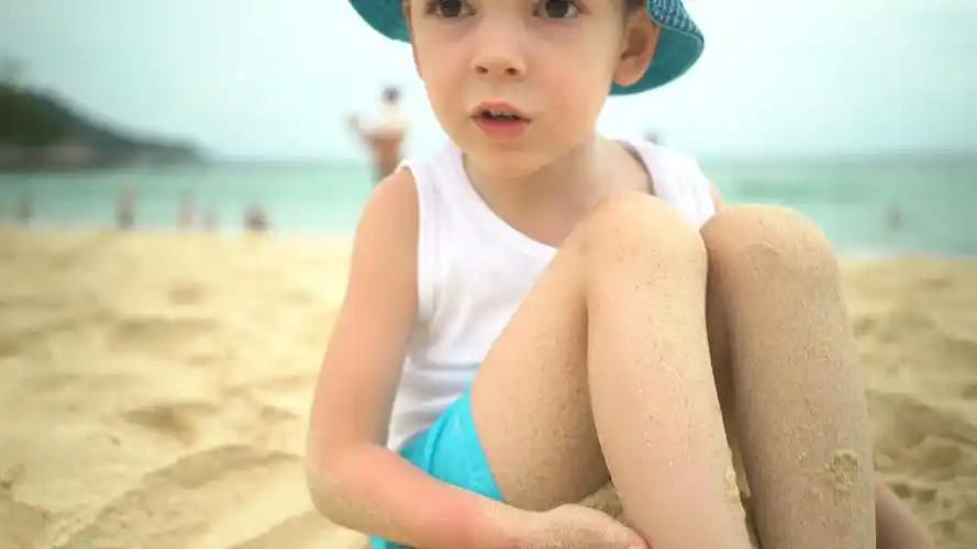 小男孩沙滩上玩沙子竖大姆指