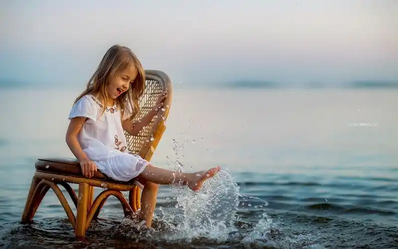 可爱的小女孩坐在椅子上玩水