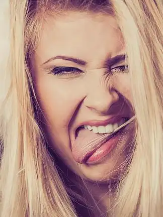 疯狂的金发女人伸出舌头的特写镜头.金发女人伸出舌头的特写